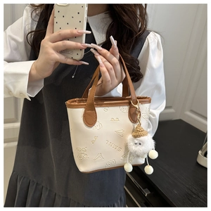 Détail du mini sac crème avec motifs de dessins animés embossés et breloque en peluche