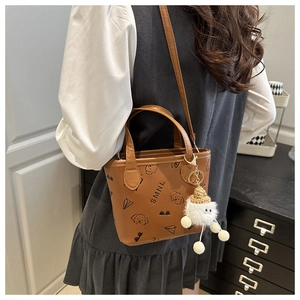 Détail du mini sac seau marron avec motifs de dessins animés et breloque en peluche sur modèle