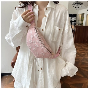 Close-up of pink crossbody bag with 3D white floral embroidery and adjustable strap