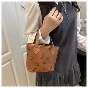 Détail d'un mini sac seau en cuir marron orné d'illustrations de dessins animés noirs