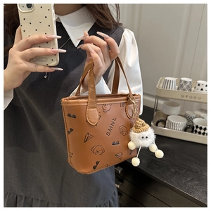 Détail d'un mini sac seau en similicuir marron avec motifs de chien et breloque peluche