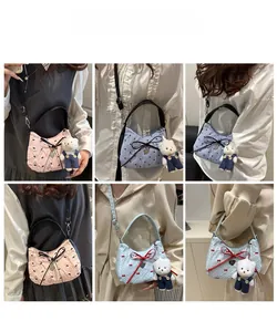 Détail de sacs demi-lune matelassés avec nœuds colorés et breloque ours en peluche