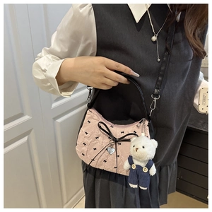 Detail of pink bubble crepe fabric handbag with black bow and cute plush bear charm