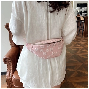 Close-up of pink floral embroidery texture and metal zipper on a canvas belt bag