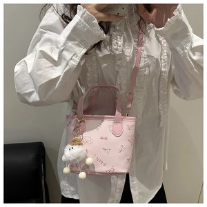 Mini sac seau rose avec imprimés dessins animés et pompon blanc porté par un mannequin