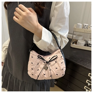 Détail du sac croissant plissé rose avec nœuds noirs et pendentif en forme de cœur
