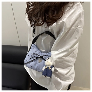 Close-up of blue striped crescent bag with black bow, heart charm and cute bear keychain