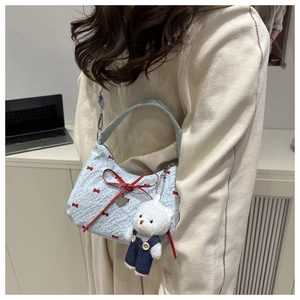 Detail of light blue crossbody bag with red bow embroidery and cute teddy bear charm