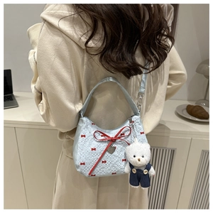 Close-up of light blue crescent bag with red bow pattern and cute teddy bear charm