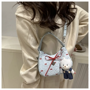 Détail du sac croissant bleu clair avec nœuds rouges et un charmant ours en peluche