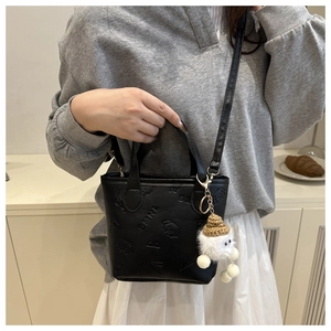 Détail du mini sac seau noir avec motifs de dessins animés gaufrés et breloque peluche