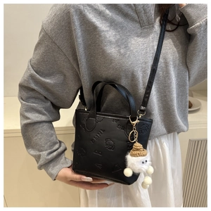 Détail du sac seau noir en similicuir avec motif chien et pendentif en peluche