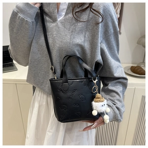 Détail du mini sac seau noir avec gaufrage chien et pendentif en peluche blanche