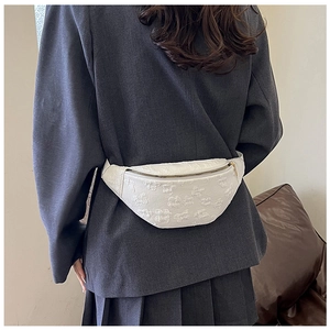 Detail of white embossed floral pattern on oxford fabric chest bag with golden zipper