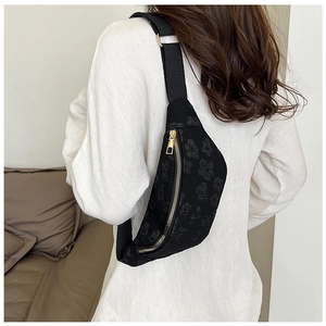 Detailed back view of a black floral jacquard saddle bag with gold zippers and strap