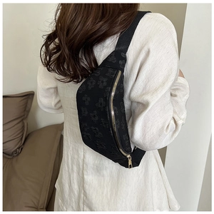 Detailed macro view of black floral textured fabric and gold zipper on crossbody bag