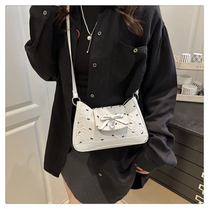 Detail of white pleated crossbody bag with black bow prints and silver heart pendant