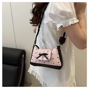 Close-up of pink pleated baguette bag featuring black bows and a silver heart pendant