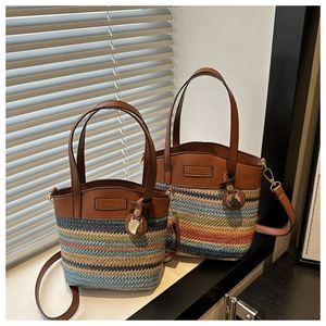 Détail de sacs seaux en paille tissée de deux tailles avec rayures arc-en-ciel et cuir