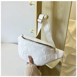 Dettaglio del tessuto bianco a fiori in rilievo su una borsa a tracolla con zip dorata