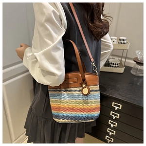 Detail of colorful woven crossbody bucket bag with brown faux leather straps and metal hardware