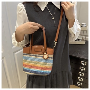 Close-up of colorful striped woven bucket bag with brown leather handle and strap