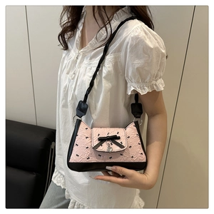 Detail of pink bow shoulder bag with heart pendant on woven handle for stylish women