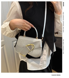 Close-up of a silver glitter saddle bag with a large gold D-ring buckle and metallic strap
