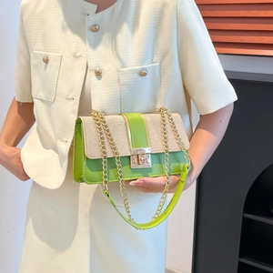 Chic beige straw and green leather shoulder bag with gold chain strap worn by a model