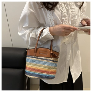 Detailed close-up of rainbow straw weave texture and brown leather handle on a bucket bag