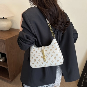 Chic off-white underarm bag with gold chain strap and monogram pattern shown on a model