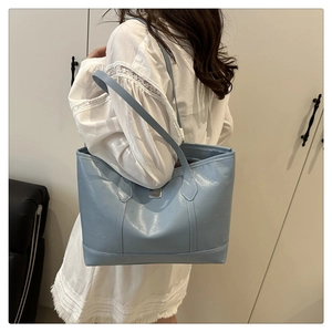 Detailaufnahme der hellblauen Leder-Tragetasche mit feiner Textur und Metallplakette