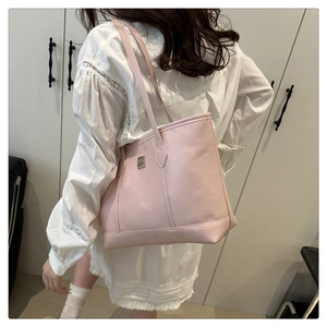Detail of pink faux leather tote bag showing embossed cartoon pattern and metal plaque