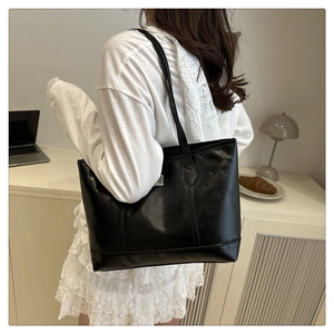 Detail view of the embossed cartoon pattern and silver logo on this black leather tote bag