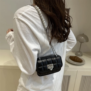 Chic black quilted crossbody bag with silver chain and pearl strap shown on a model
