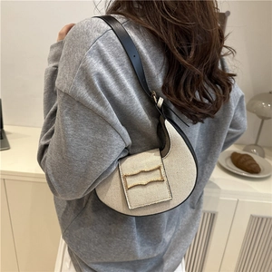Sac hobo minimaliste crème avec boucle dorée et bandoulière noire porté par un modèle