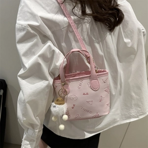 Mini sac seau rose en cuir avec motifs embossés et pompon porté par un mannequin en été