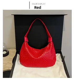 Detail of red crescent shoulder bag with woven texture in a black gift box setup