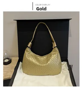 Detail of gold woven hobo shoulder bag with a metallic finish inside a premium gift box