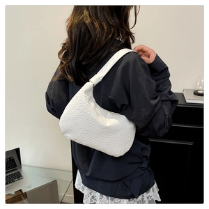 Detail of white woven leather hobo bag showing the intricate texture and minimalist strap