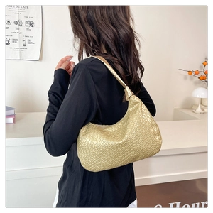 Detail of gold crescent hobo bag featuring woven texture worn by a model in a cafe