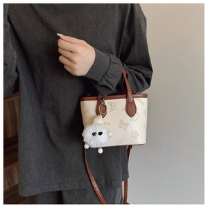 Detail of butterfly embossed bucket bag with detachable plush charm and leather strap