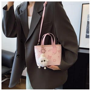 Pink PU bucket bag with butterfly prints and plush charm shown on a fashion model