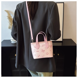 Detail of light pink bucket bag with cartoon patterns worn across the waist