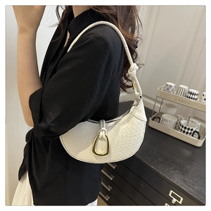Detail view of woven leather crescent bag with gold D-ring and knotted shoulder strap
