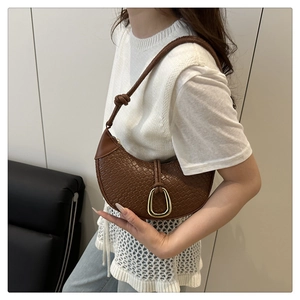 Close-up of brown woven texture hobo bag with gold hardware ring on a model