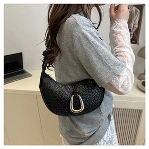 Detail of black woven crescent bag featuring a metallic gold-tone horseshoe buckle