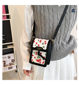 Detail of sweet small square bag featuring cherry pattern print and fashion logo label