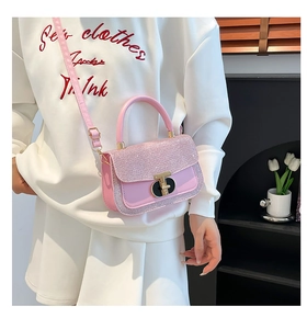 Pink glitter crossbody bag with wave flap and lock shown on a white casual outfit