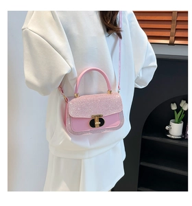 Close-up of pink sequined crossbody bag with gold metal lock on a female model